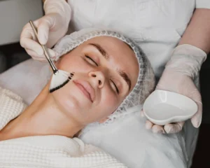 A woman with radiant, healthy skin demonstrates the application of summer-safe chemical peels at Skincare Sommelier NYC.